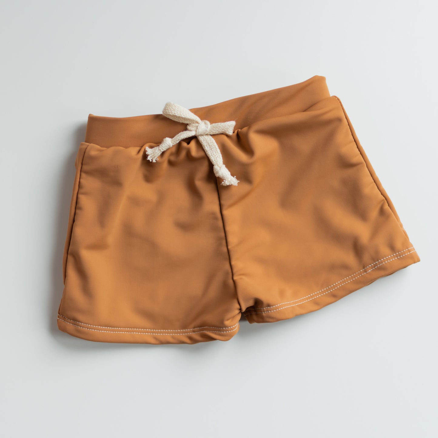 Light brown shorts with a white drawstring on a light gray background