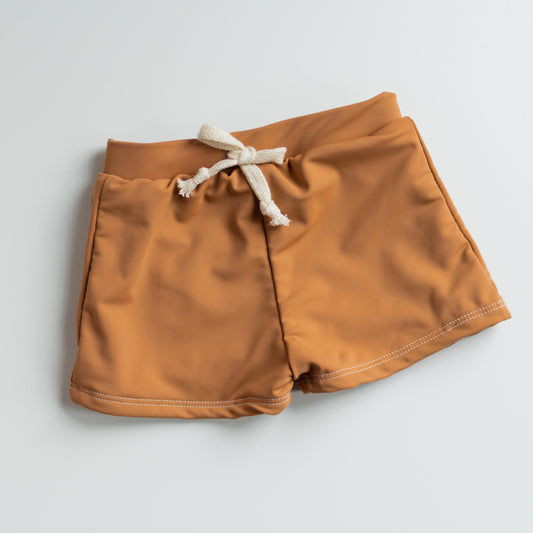Light brown shorts with a white drawstring on a light gray background