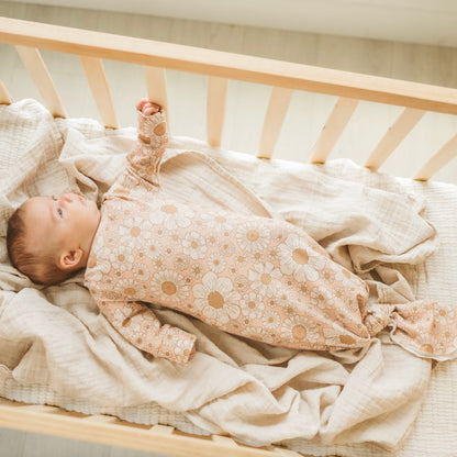 Baby in a crib with light pink flower newborn gown.