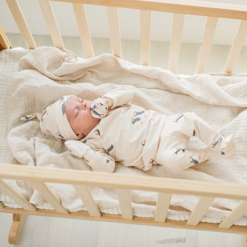 Newborn baby sleeping in a wooden crib with a white blanket