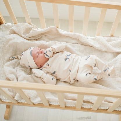 Newborn baby sleeping in a wooden crib with a white blanket